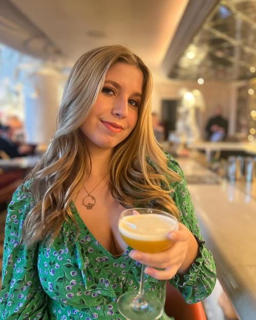 Woman holding a cocktail at a bar.