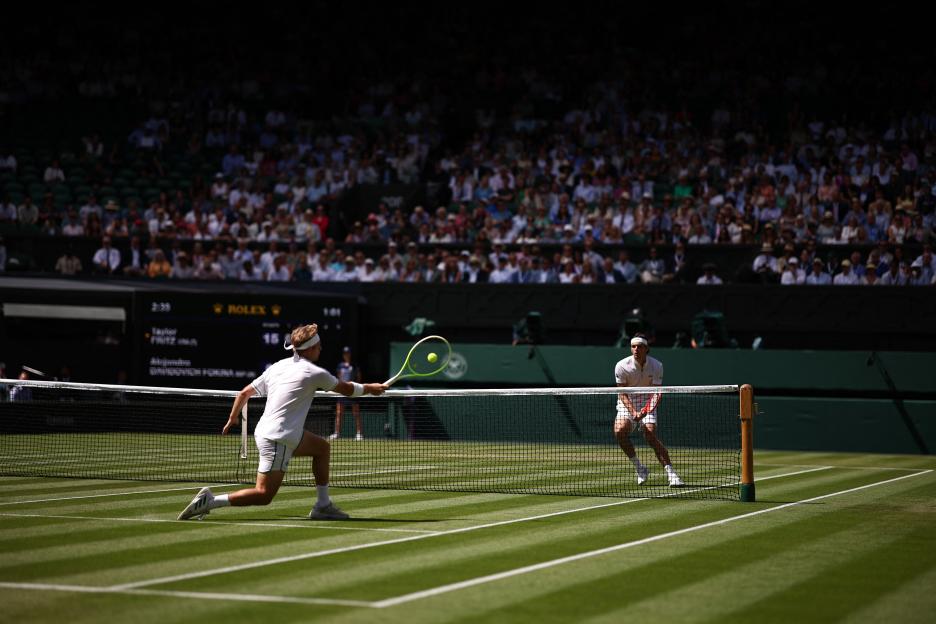 Tennis match at Wimbledon; player hitting forehand return.
