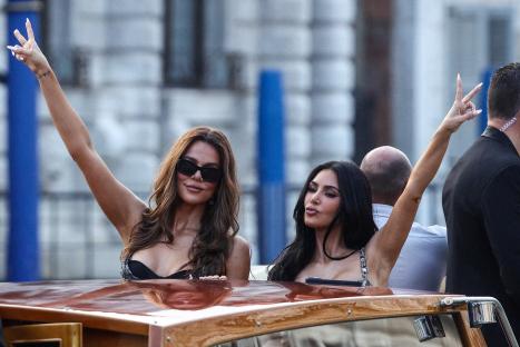 Khloe and Kim Kardashian waving from a boat.