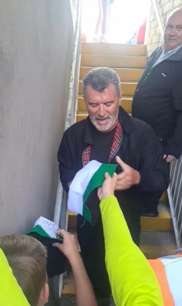 Roy Keane signing a hat.