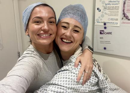 Two smiling women in hospital caps embrace.