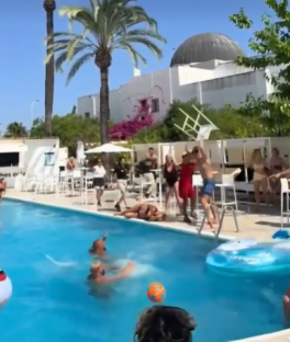 People swimming and playing in a pool; a chair is falling.