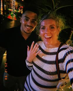 Photo of a couple, the woman showing off her engagement ring.