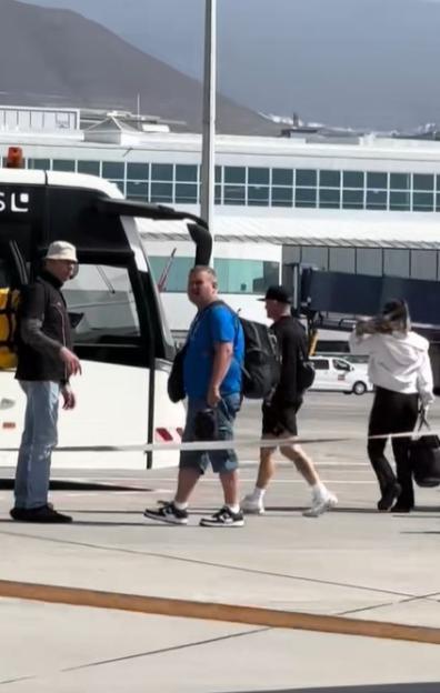 People walking at an airport near a bus.