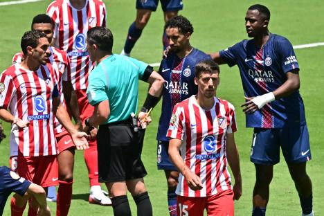 Soccer players arguing with a referee after a red card.