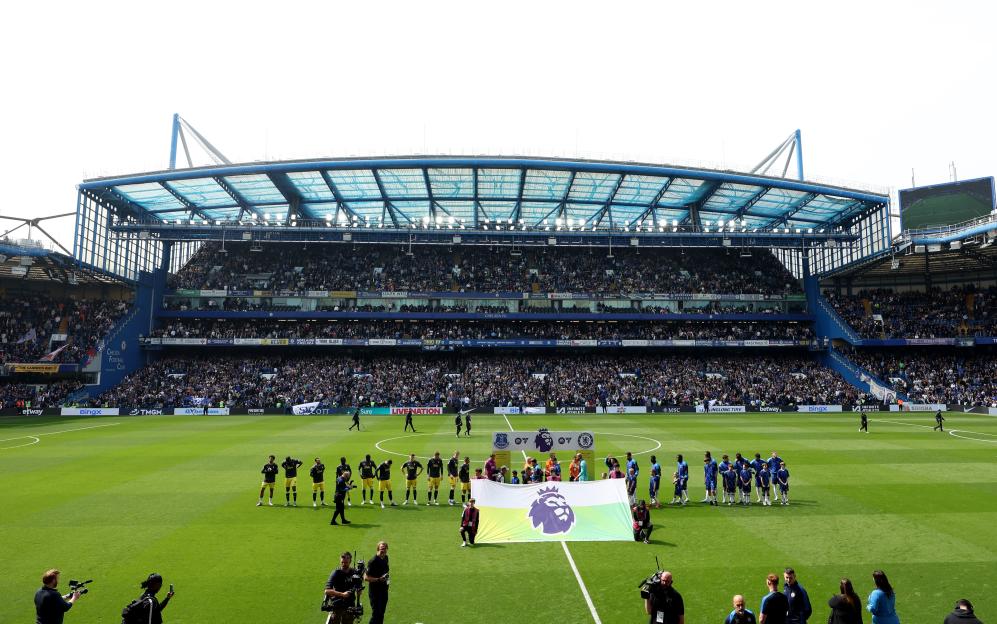 Soccer players line up on the field at Stamford Bridge before a Premier League match.