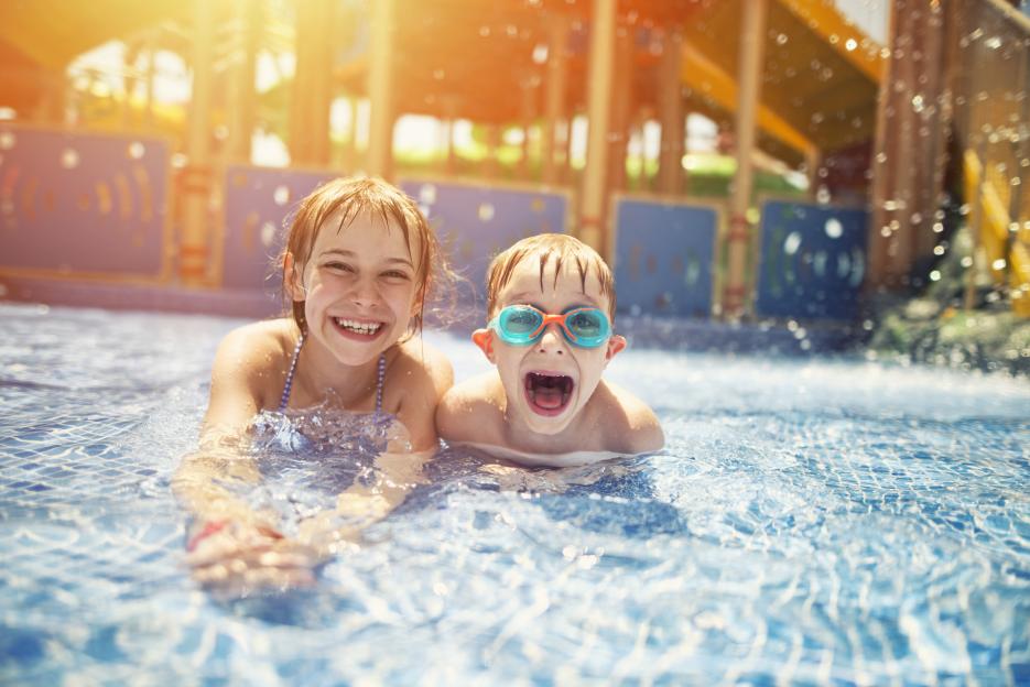 Girl and boy smiling in a pool.