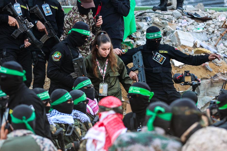 A female hostage being handed over to a Red Cross team by Hamas militants.