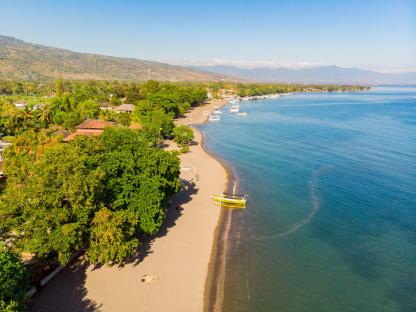 Aerial view of Lovina beach in North Bali, Indonesia, showing boats on the shore and people relaxing on the sand.