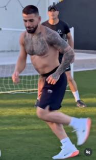 Shirtless soccer player running on a field.