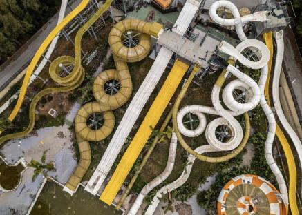 Aerial view of an abandoned water park with overgrown vegetation.