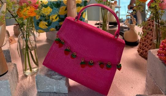 Pink handbag with strawberry accents.