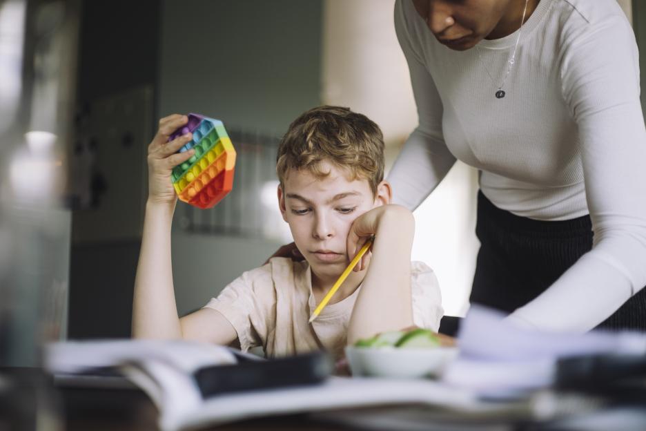 A mother assists her son with his homework.