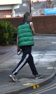 Person walking down a street carrying a can.
