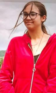 Woman in red zip-up jacket and glasses.