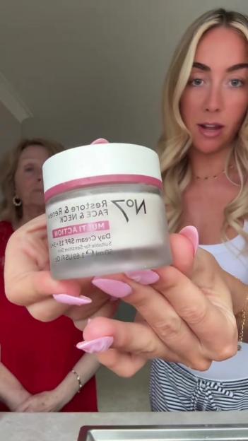 Woman holding jar of No7 face cream.