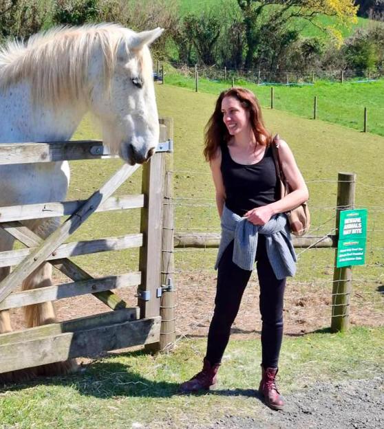 Woman looking at a white horse through a wooden fence.