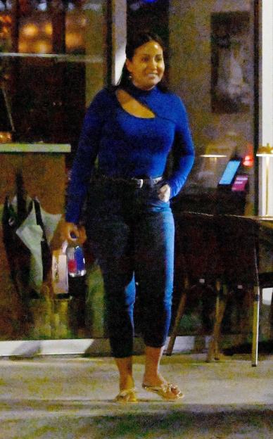 Woman in blue top and jeans walking outside at night.
