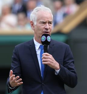 John McEnroe speaking into a microphone at Wimbledon.