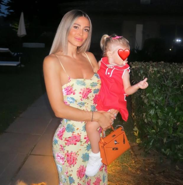Woman in floral dress holding a toddler.