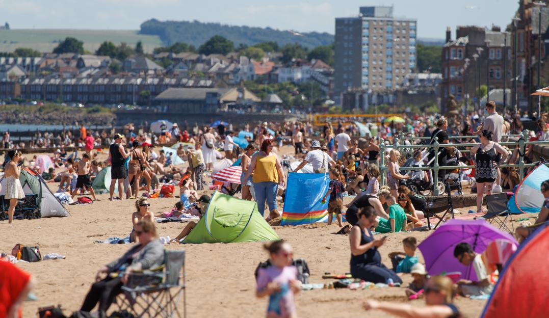 Crowded Portobello Beach in Edinburgh on a warm day.