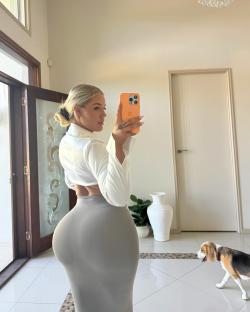 Woman taking a selfie in a white shirt and grey skirt.