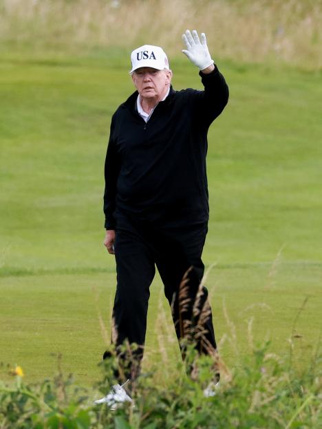 Donald Trump waving on a golf course.