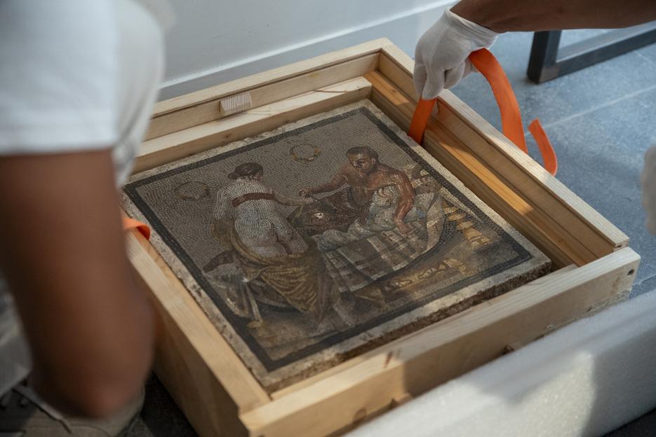 Ancient Roman mosaic depicting a half-naked couple being installed at the Pompeii Archaeological Park.