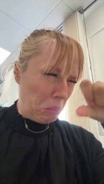 Woman crying and holding her nose.