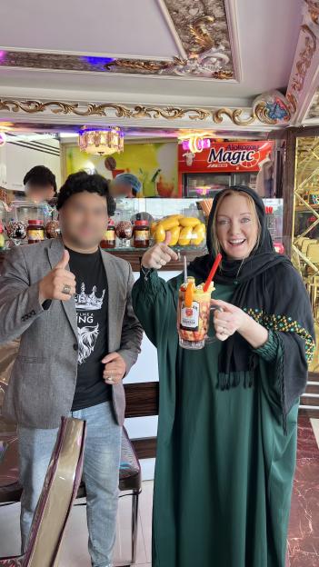 Woman in Afghanistan holding a fruit drink with a man giving a thumbs up.