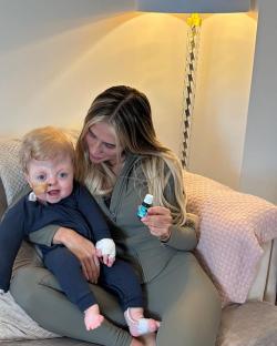 Woman holding baby and essential oil bottle.