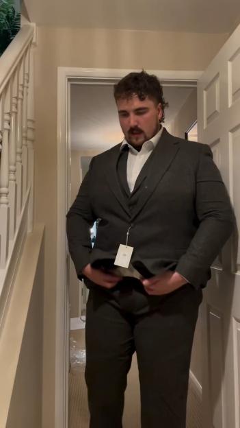 Man in a suit adjusting his jacket.