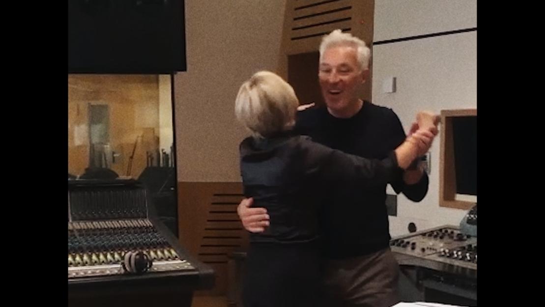 Two people embracing in a recording studio.