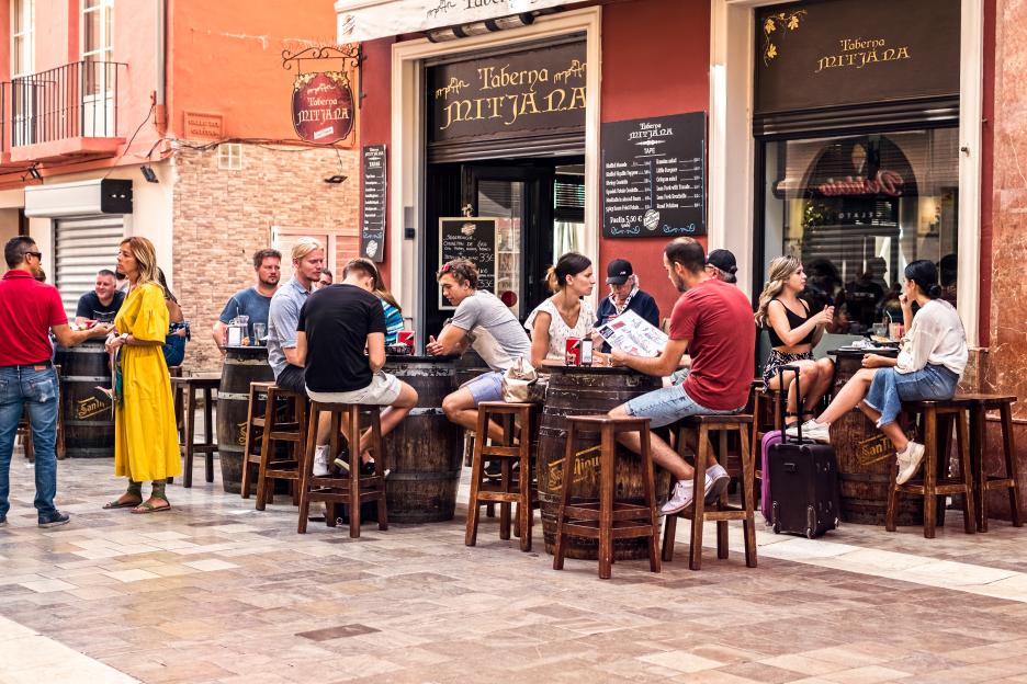 Tourists eating and drinking at an outdoor restaurant in Malaga, Spain.
