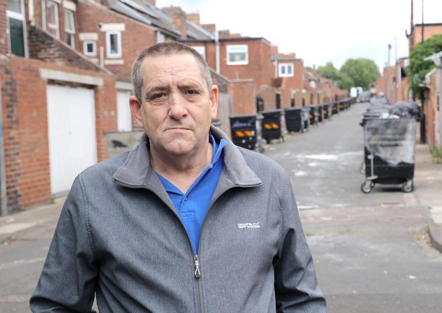 A man stands in a back alley, concerned about giant rats.