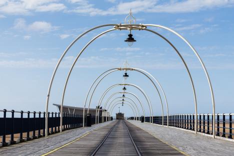 Empty pier with arched lamp posts.
