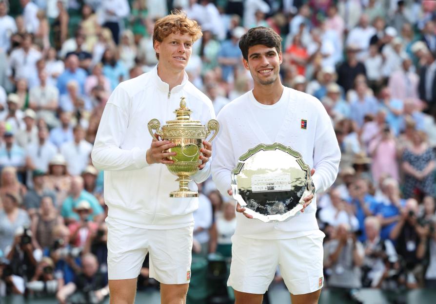 Jannik Sinner and Carlos Alcaraz holding their Wimbledon trophies.