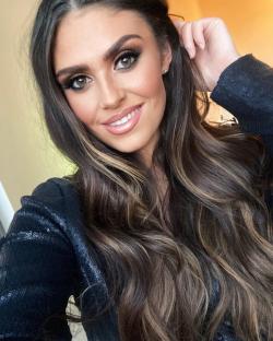 Close-up portrait of a woman with long brown hair and makeup.