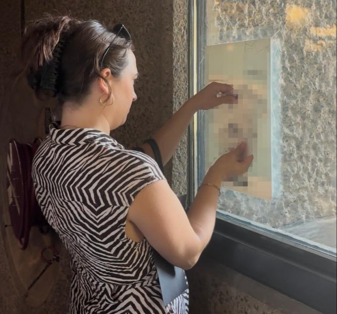Woman looking at a notice on a window.