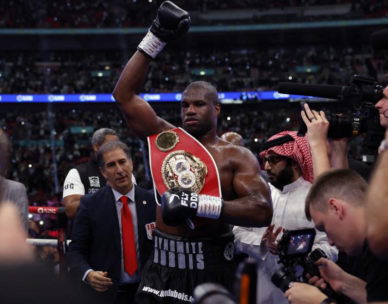 Daniel Dubois celebrates a boxing victory, holding up his championship belt.