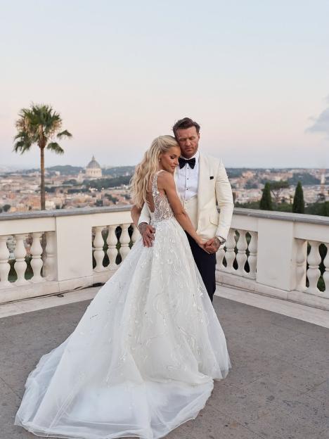 Bride and groom embracing on a balcony overlooking a city.