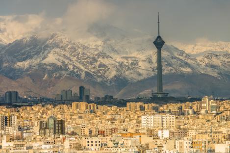 Tehran skyline with Milad Tower and snow-capped mountains in the background.