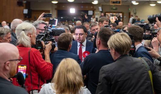 A politician surrounded by journalists and cameras.