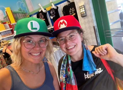 Two women wearing Mario and Luigi hats.