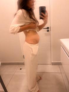 Woman taking a selfie of her swollen abdomen.