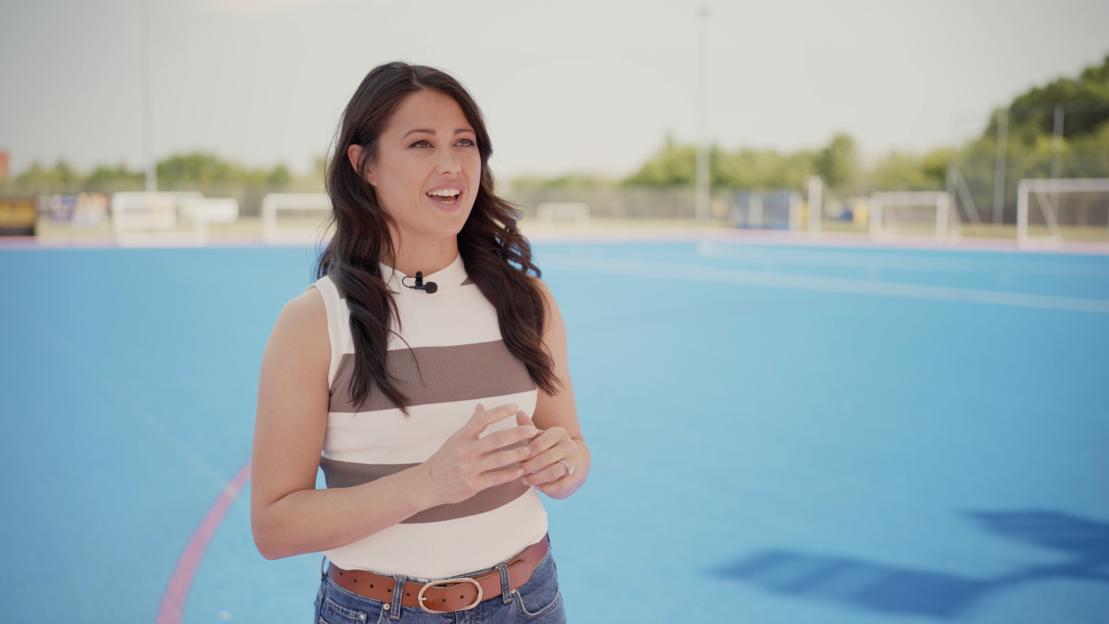 Sam Quek, Olympic gold medalist in hockey, speaking on a hockey field.