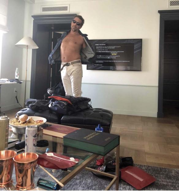Shirtless man in hotel room.