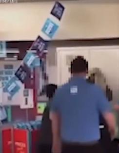 Man in blue shirt stands in a shop as cards fall from the ceiling.