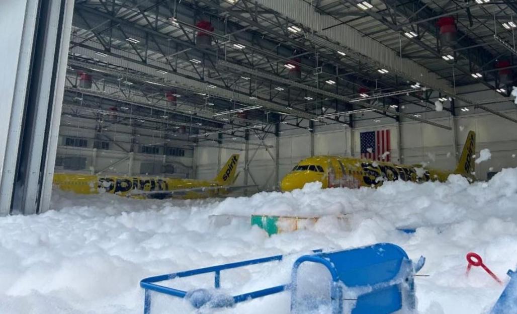Two Spirit Airlines planes covered in foam inside a hangar.