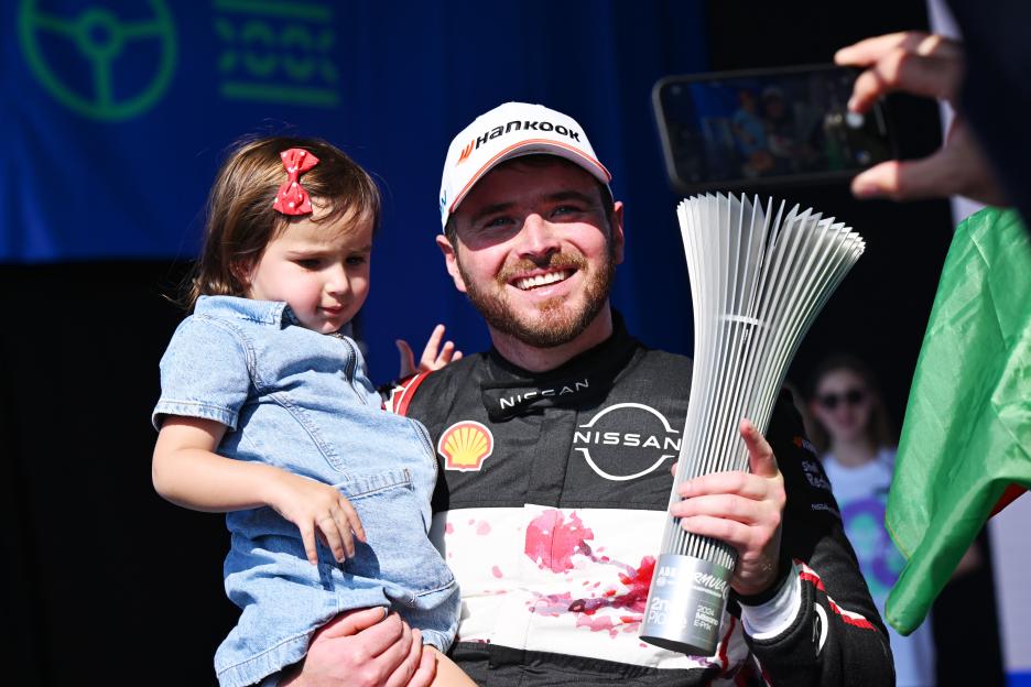 Oliver Rowland, Nissan Formula E Team, on the podium with his daughter and trophy.